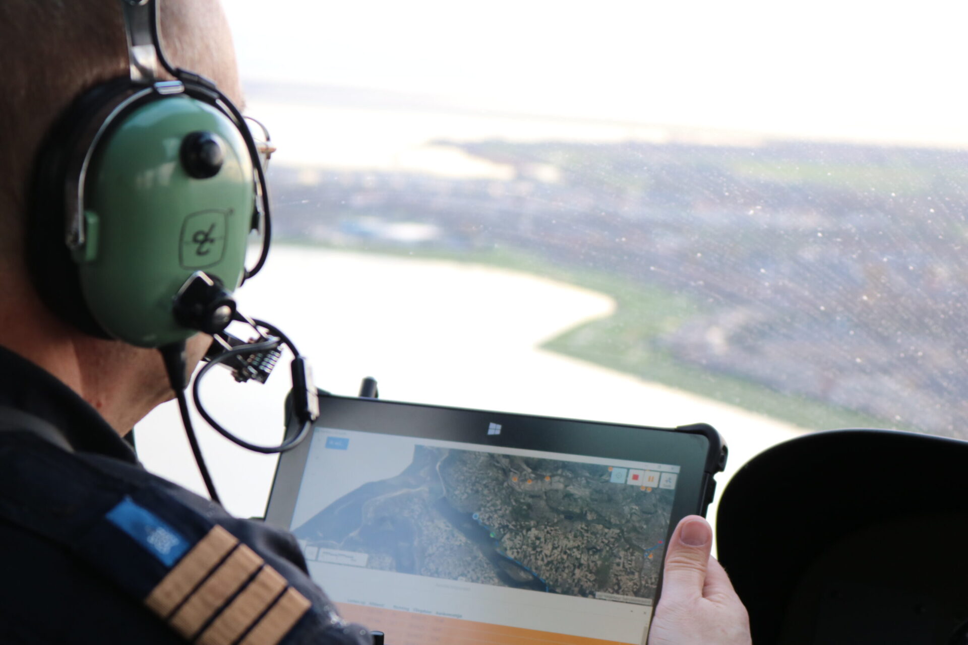 Foto in de cockpit. Je ziet iemand op een tablet met de GeoWeb-oplossing LIS werken. 